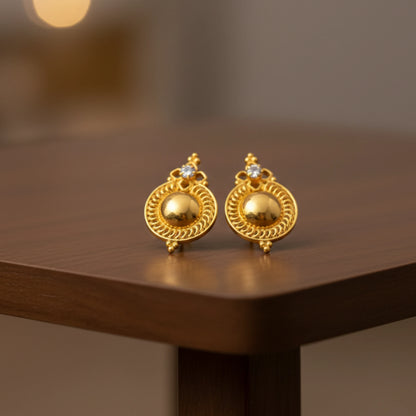 Pair of gold plated Dome stud earrings on a wooden surface with a blurred background