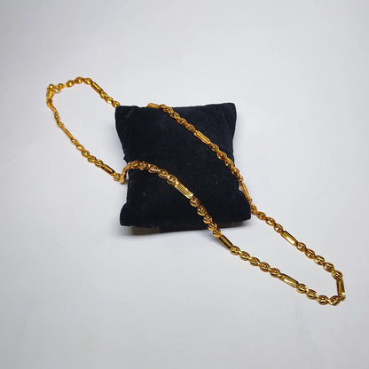  gold plated neckchain with beads and cylindrical pattern on a black cushion