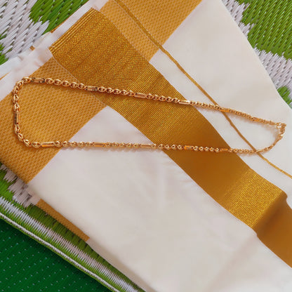 Gold plated neck chain with beads and cylindrical pattern on a fabric background with green and white pattern