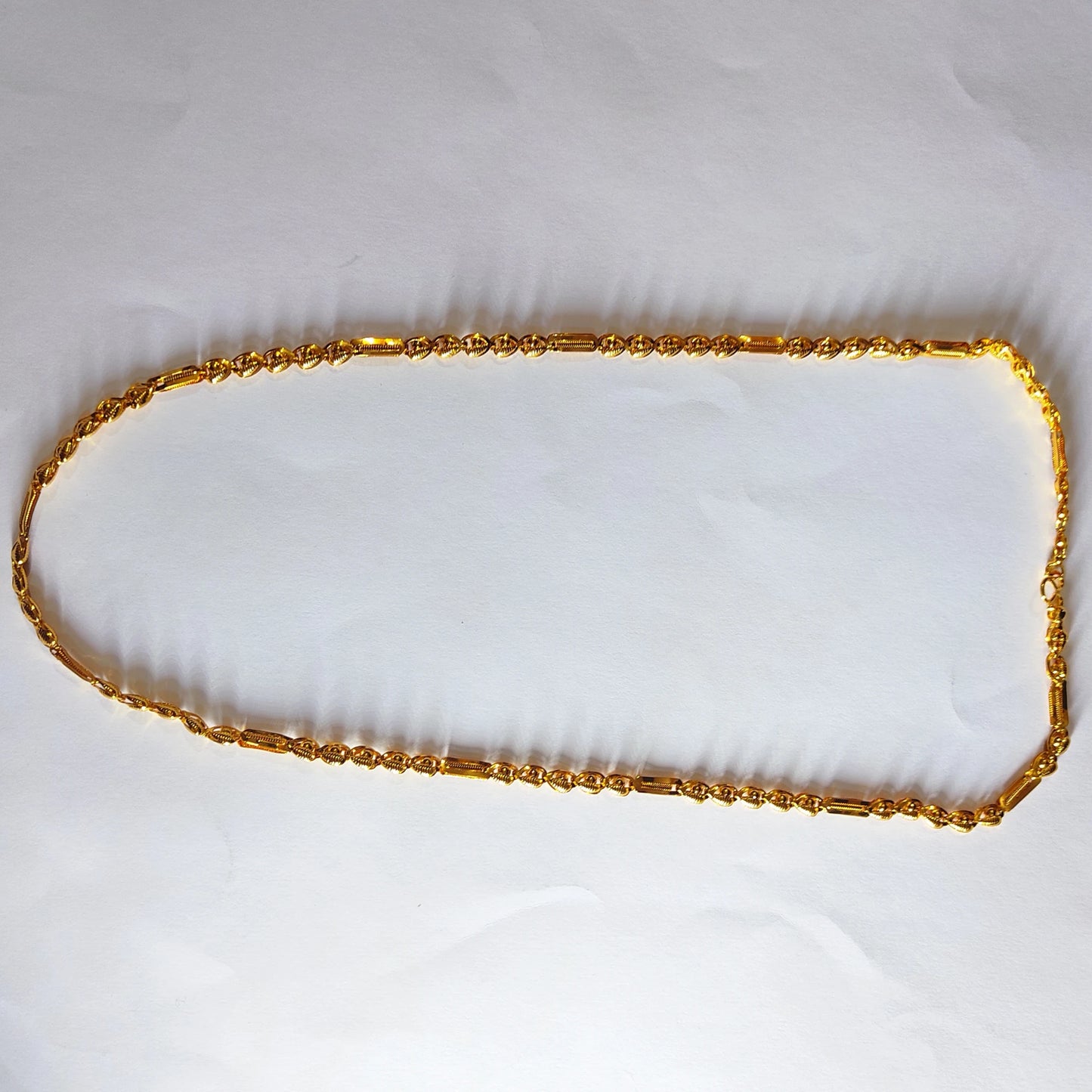 Gold plated neck chain on a white fabric background