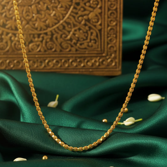 Gold plated neckchain on a green fabric background with an ornate box in the background