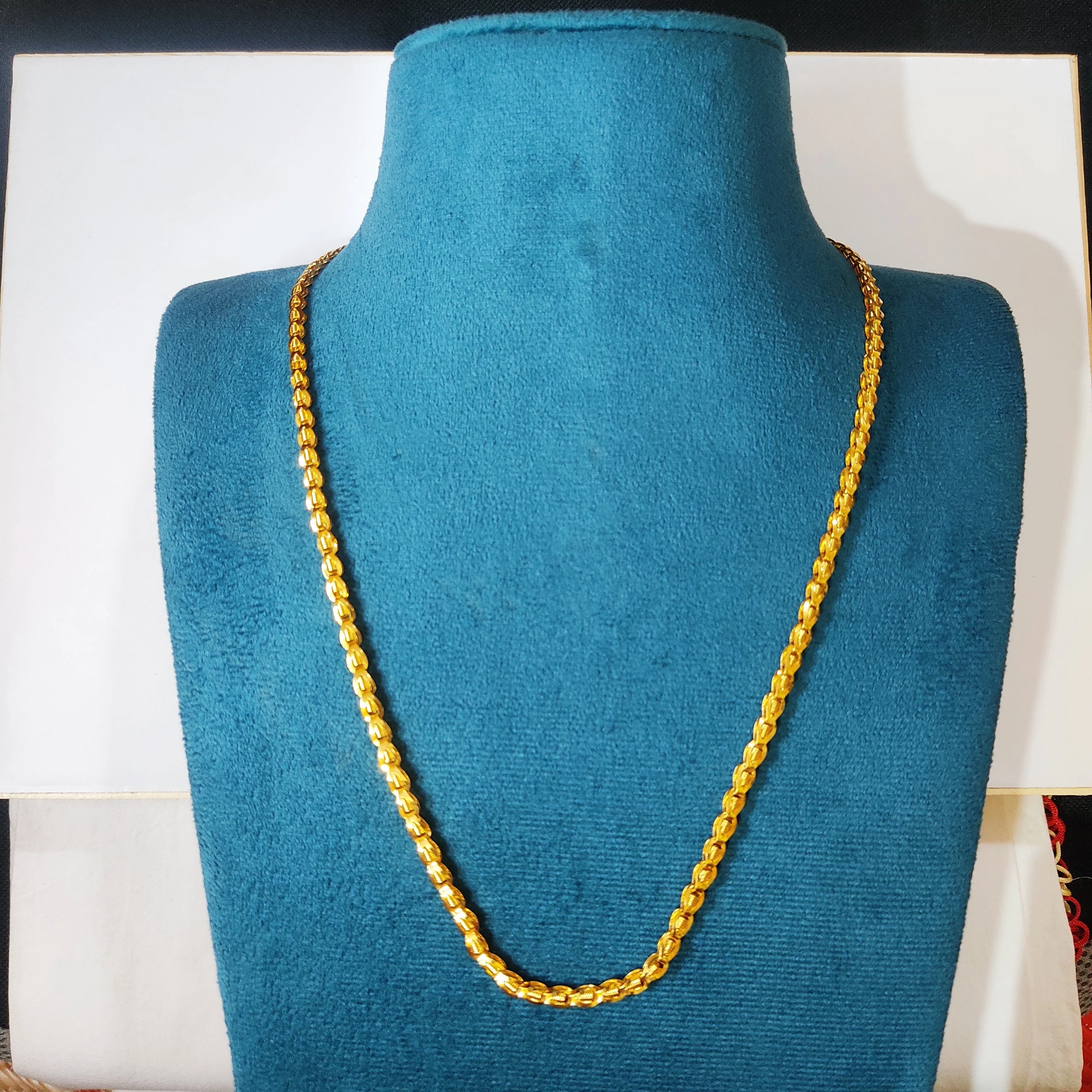 Gold plated neckchain on a blue mannequin bust