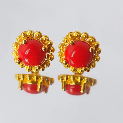 Pair of  round red earrings with gold plating decorative elements on a light gray background