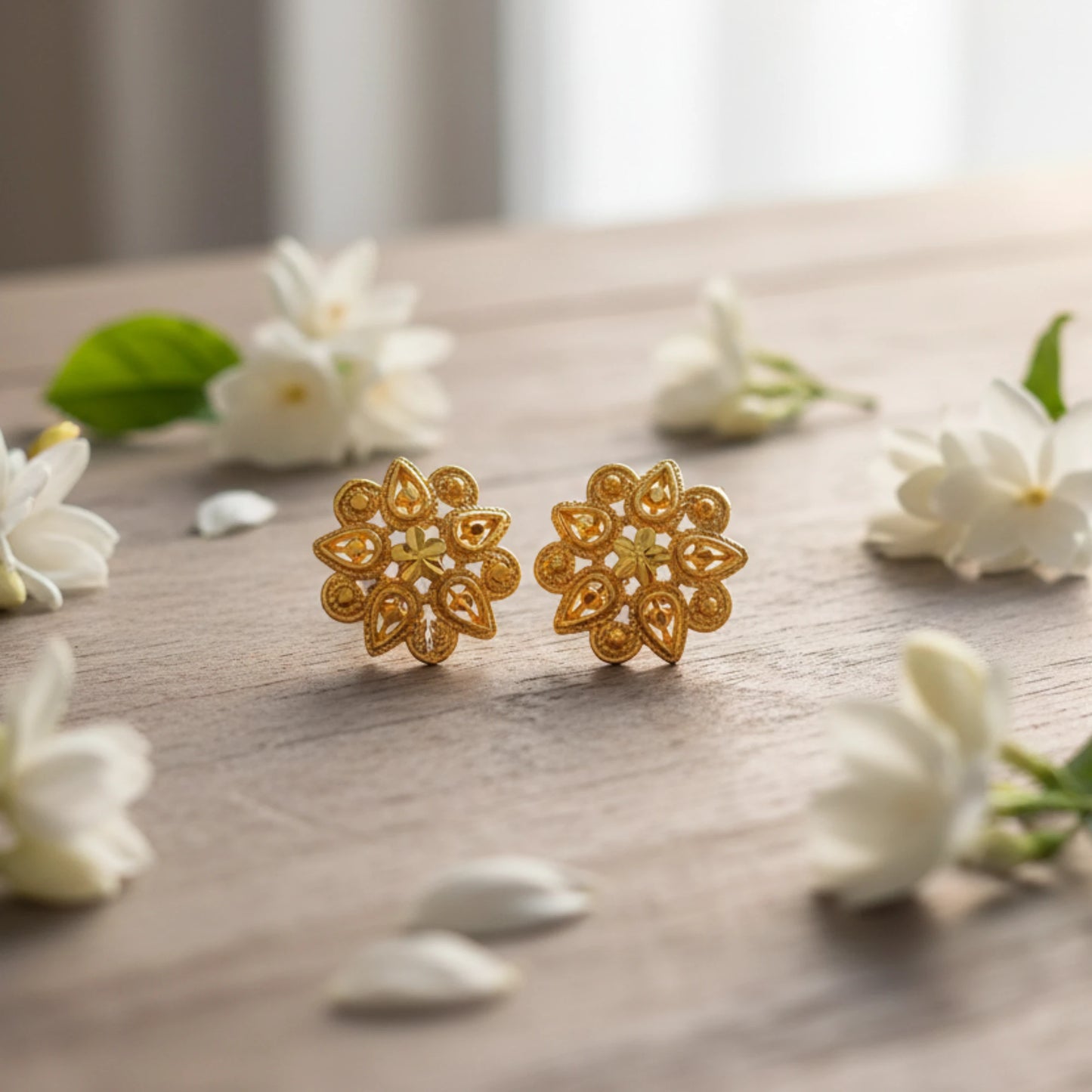 Gold plated Indian Classic floral earrings on a wooden surface with white flowers