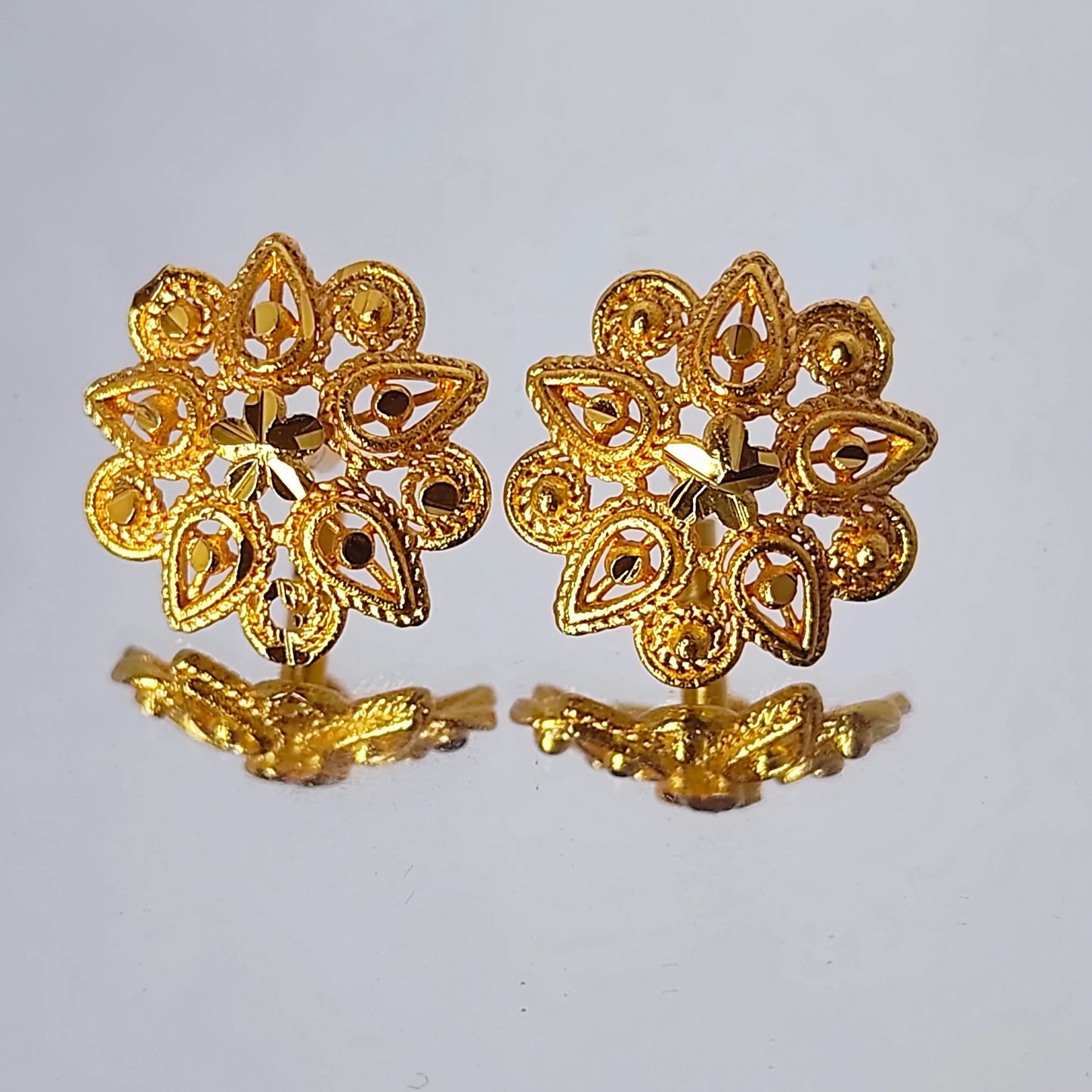 Pair of gold plated Indian Classic floral earrings on a light gray background