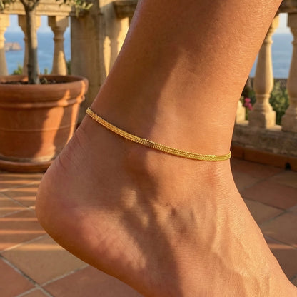 Gold plated anklet on a foot with a scenic background