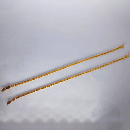 Gold plated anklets on a light gray background