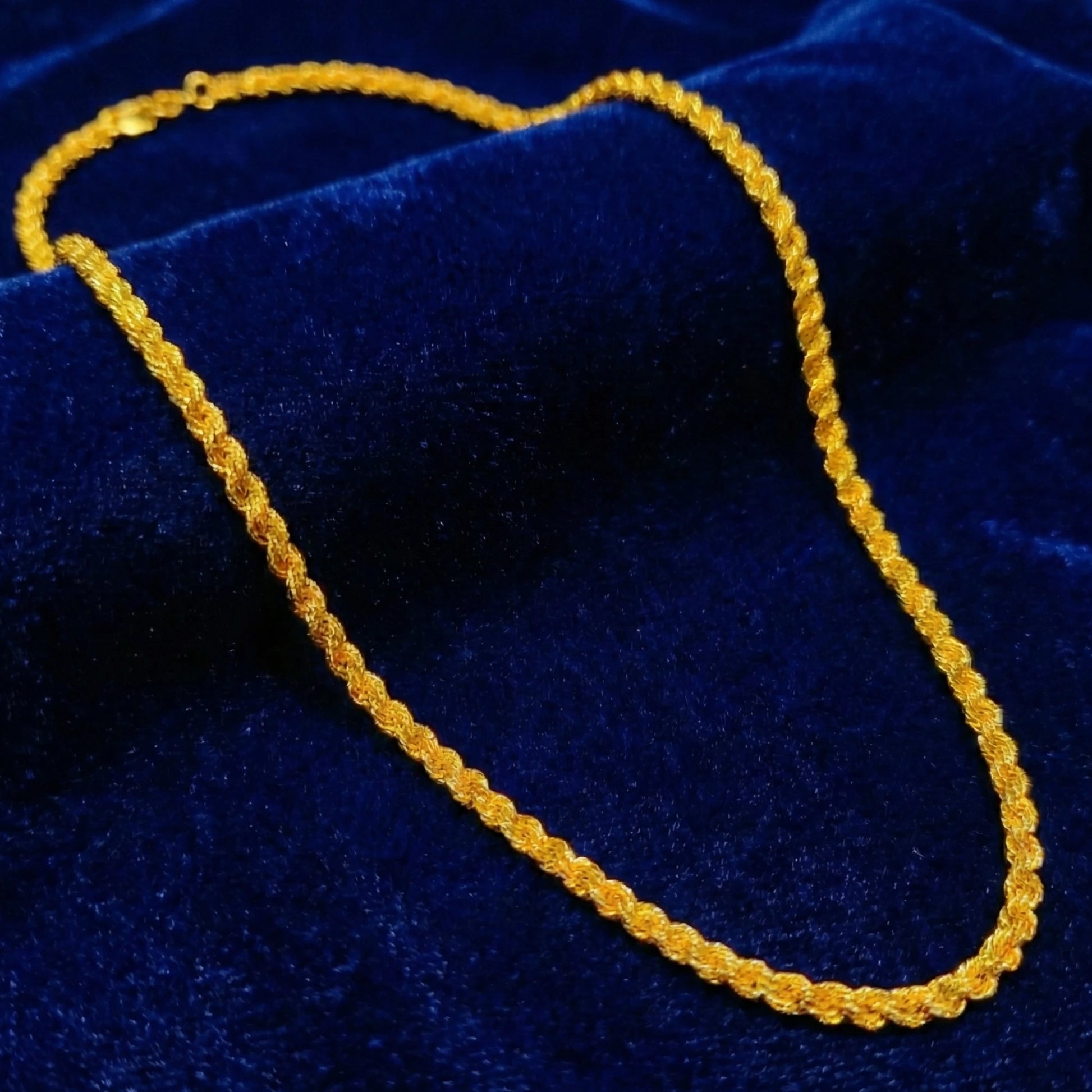 Gold plated rope neckchain on a blue velvet background