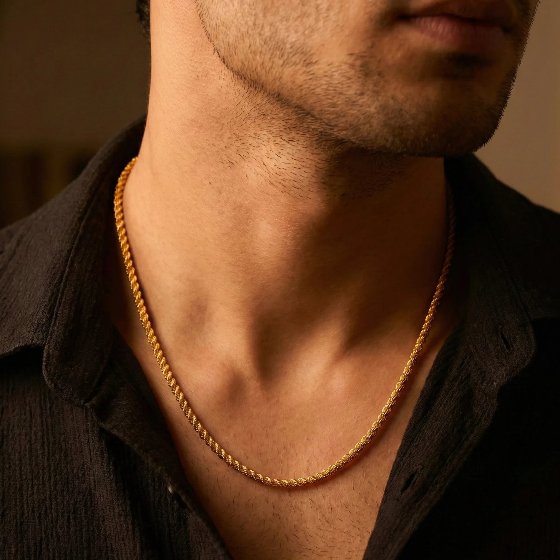 Close-up of a person wearing a gold plated rope neck chain with a blurred background