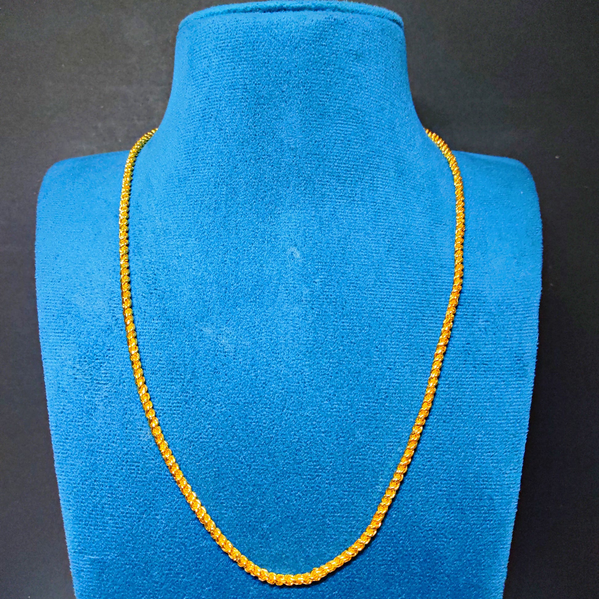 Gold Plated necklace on a blue velvet mannequin bust against a black background