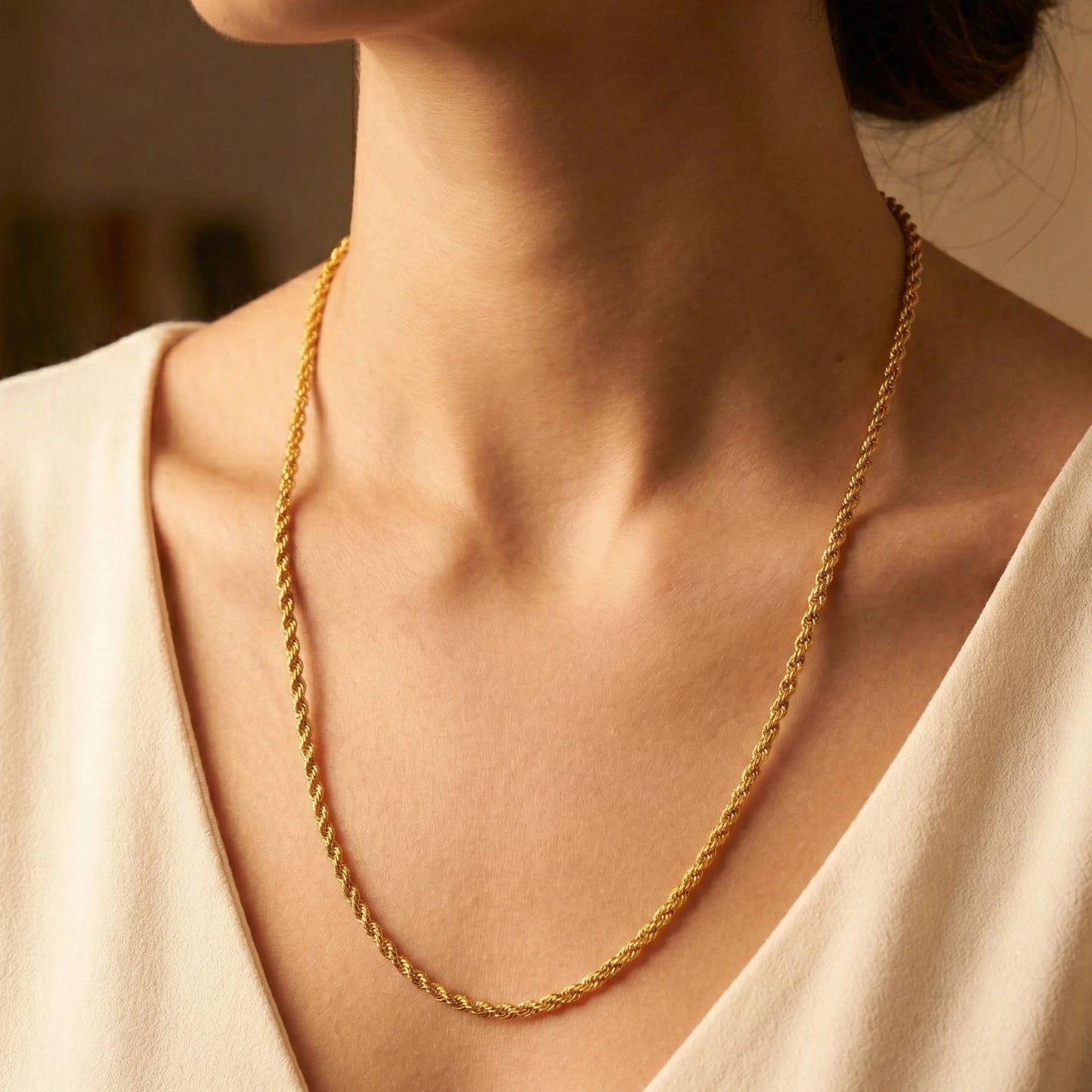 Gold plated rope neckchain worn by a person with a neutral background