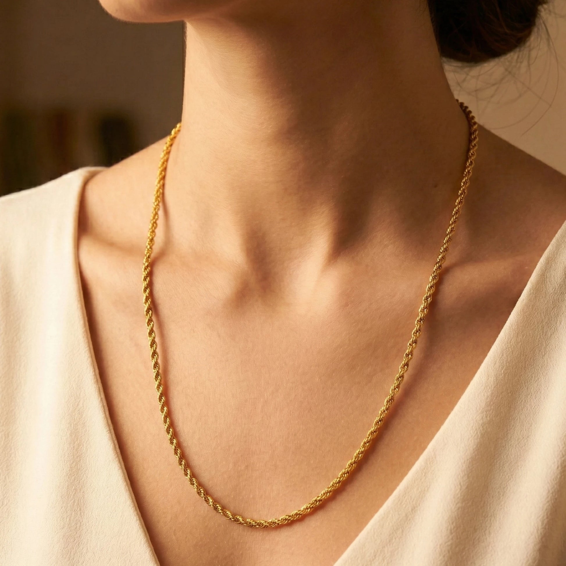Gold plated rope neckchain worn by a person with a neutral background