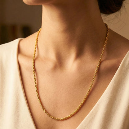 Gold plated rope neckchain worn by a person with a neutral background