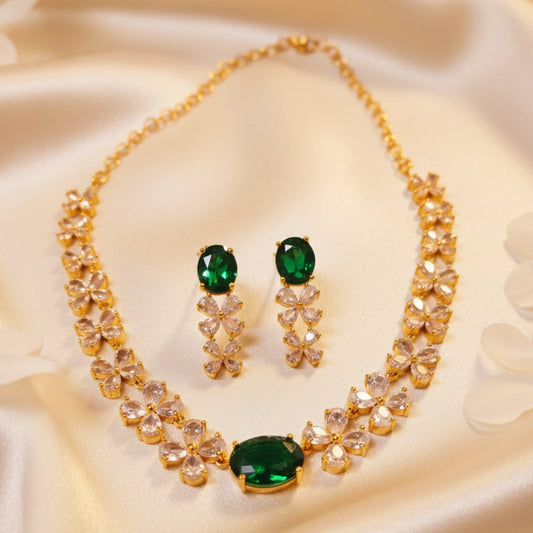 Gold plated necklace and earrings with green AD stones on a beige fabric background