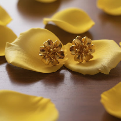Gold plated flower-shaped earrings on yellow petals with a wooden background