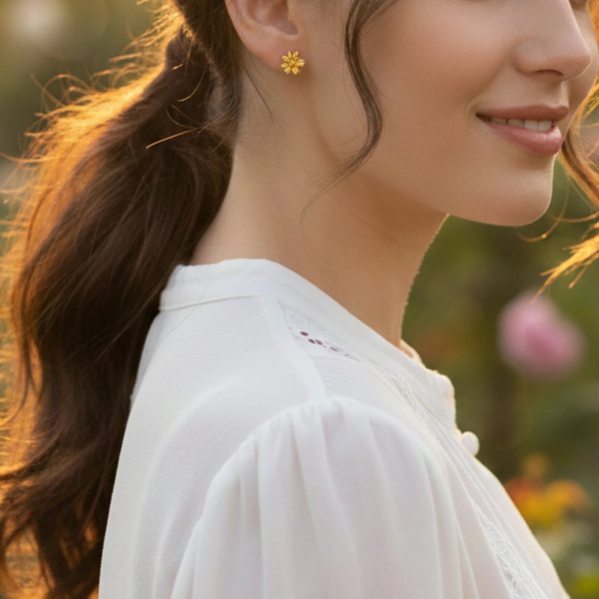 Woman wearing gold plated flower earrings with a blurred natural background
