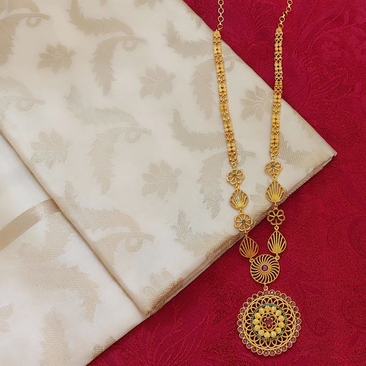 Gold plated long ethnic necklace with intricate design and a floral mandala pendant on a red and beige fabric background