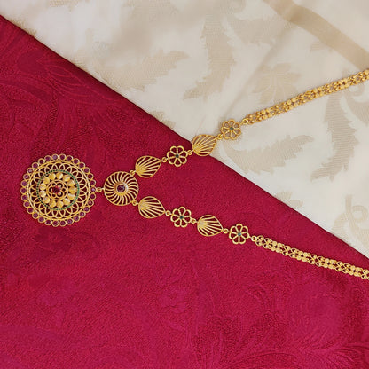 Gold plated long necklace with floral mandala pendant on a red and beige fabric background