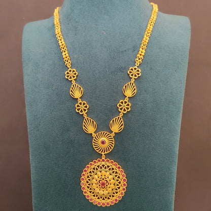 Gold plated long ethnic necklace with intricate design and a floral mandala pendant on a green velvet stand against a brown background