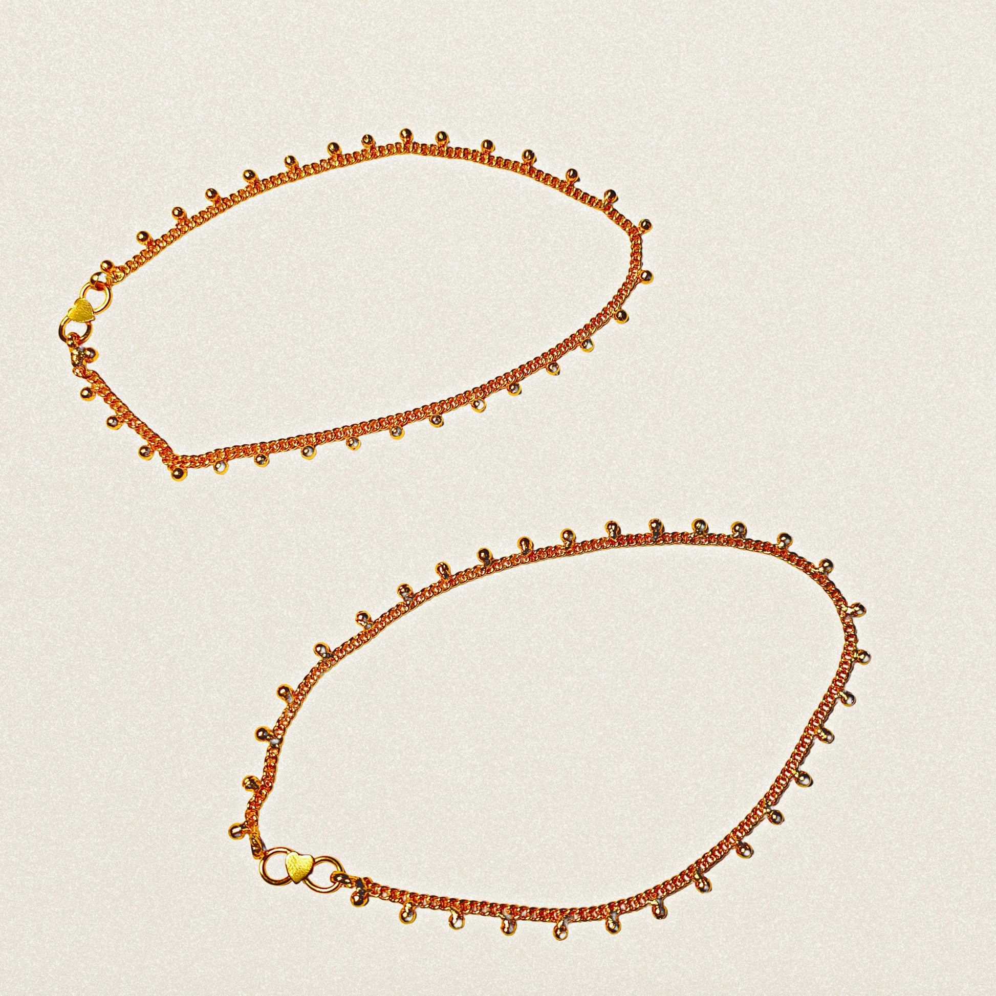 Two gold plated Anklets on a beige background