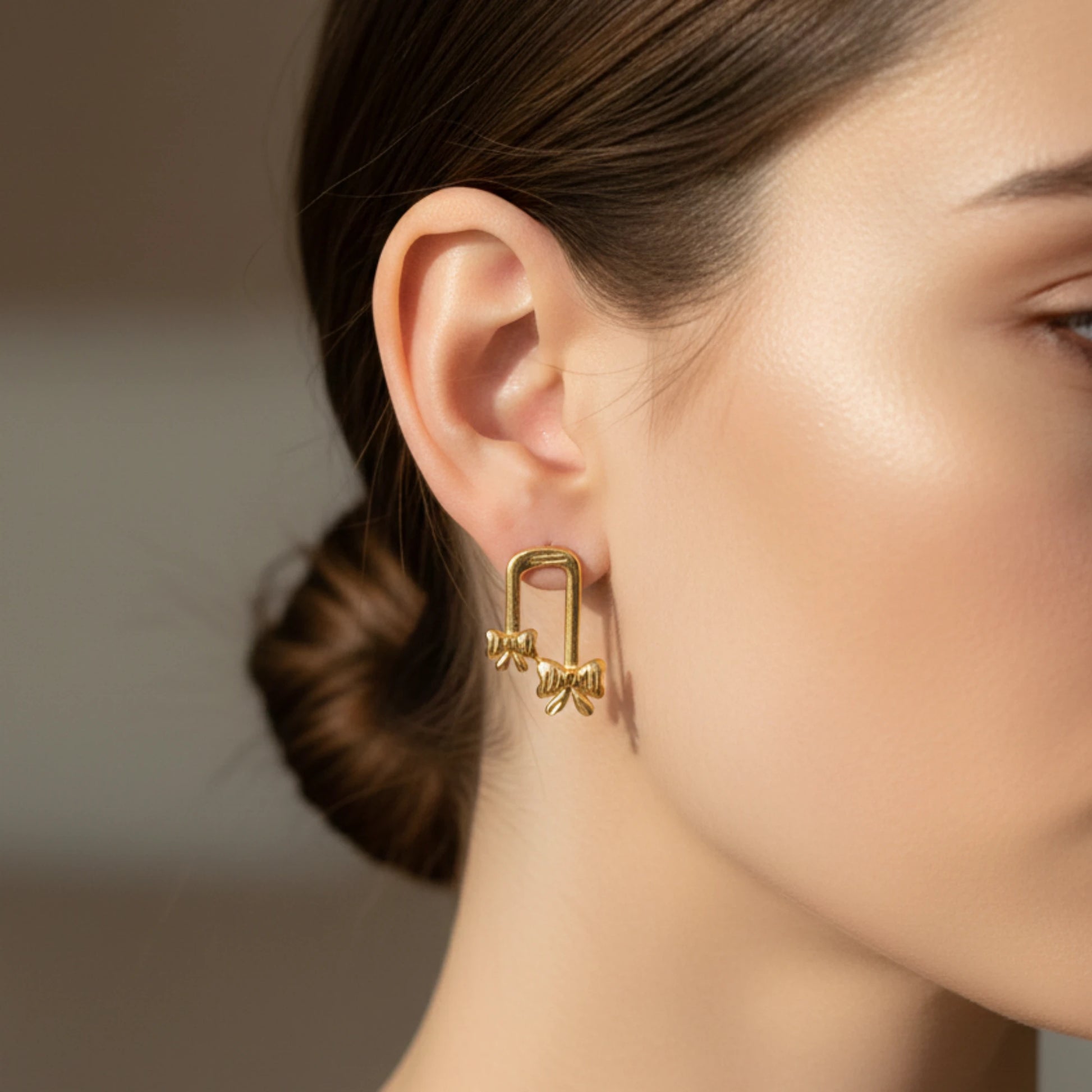 Gold plated Bow Shaped earring worn by a person with a neutral background
