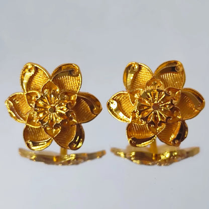 Pair of gold plated flower-shaped earrings on a light gray background