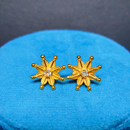 Gold Plated star-shaped earrings with a central gemstone on a blue cushion.