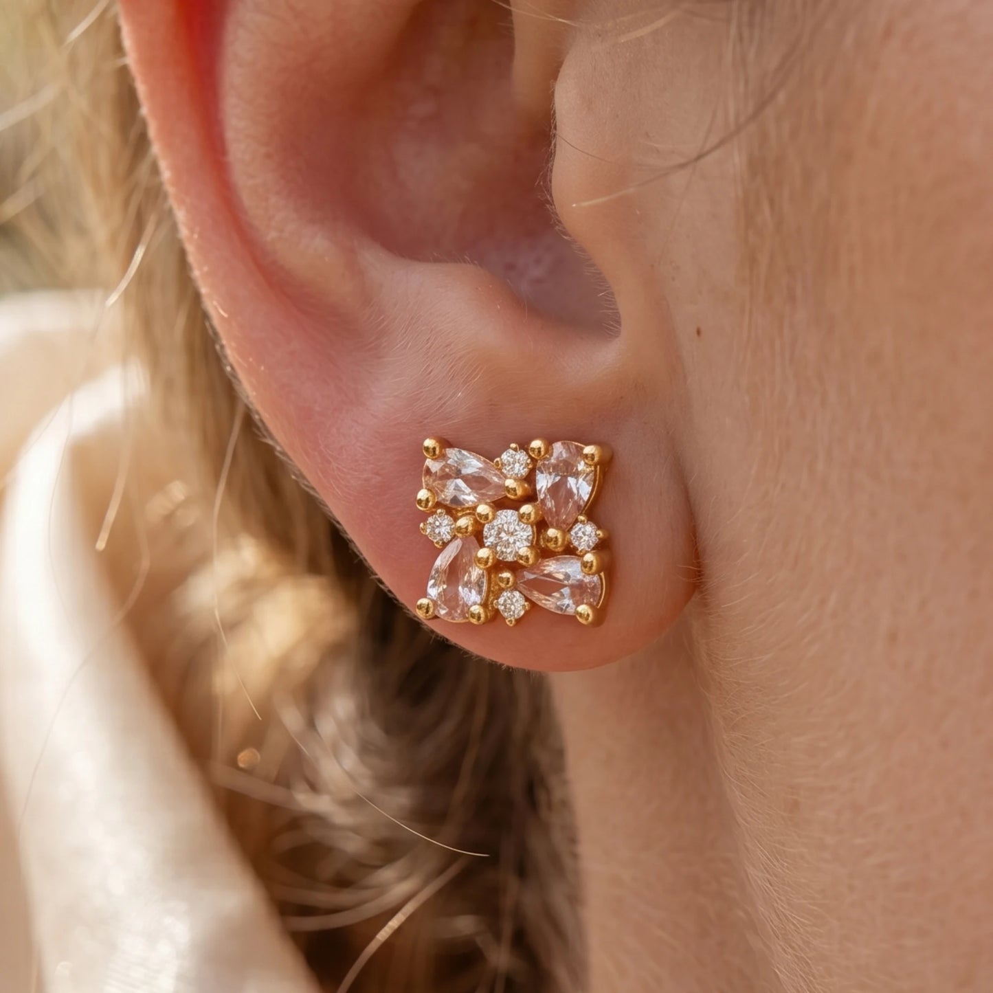 Model wearing a gold plated floral cluster earrings with Ad stones both in tear shaped and round shaped pattern arranged in a intricate manner
