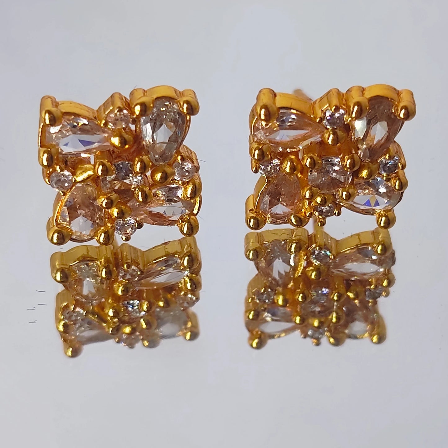 A gold plated floral cluster earrings with Ad stones both in tear shaped and round shaped pattern arranged in a intricate manner