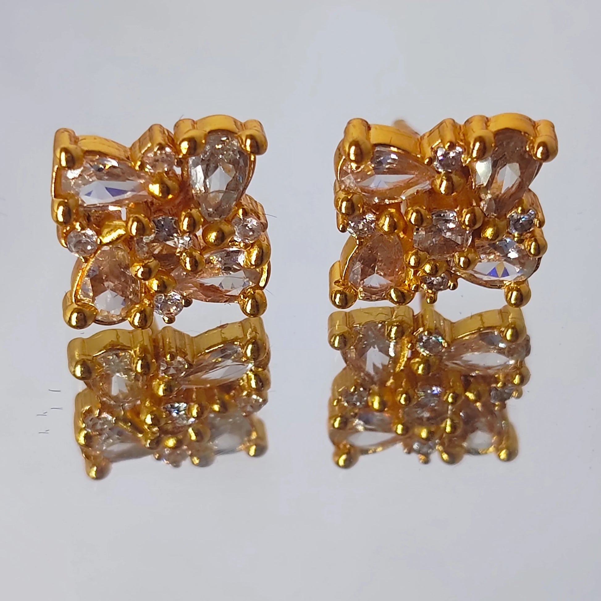 A gold plated floral cluster earrings with Ad stones both in tear shaped and round shaped pattern arranged in a intricate manner