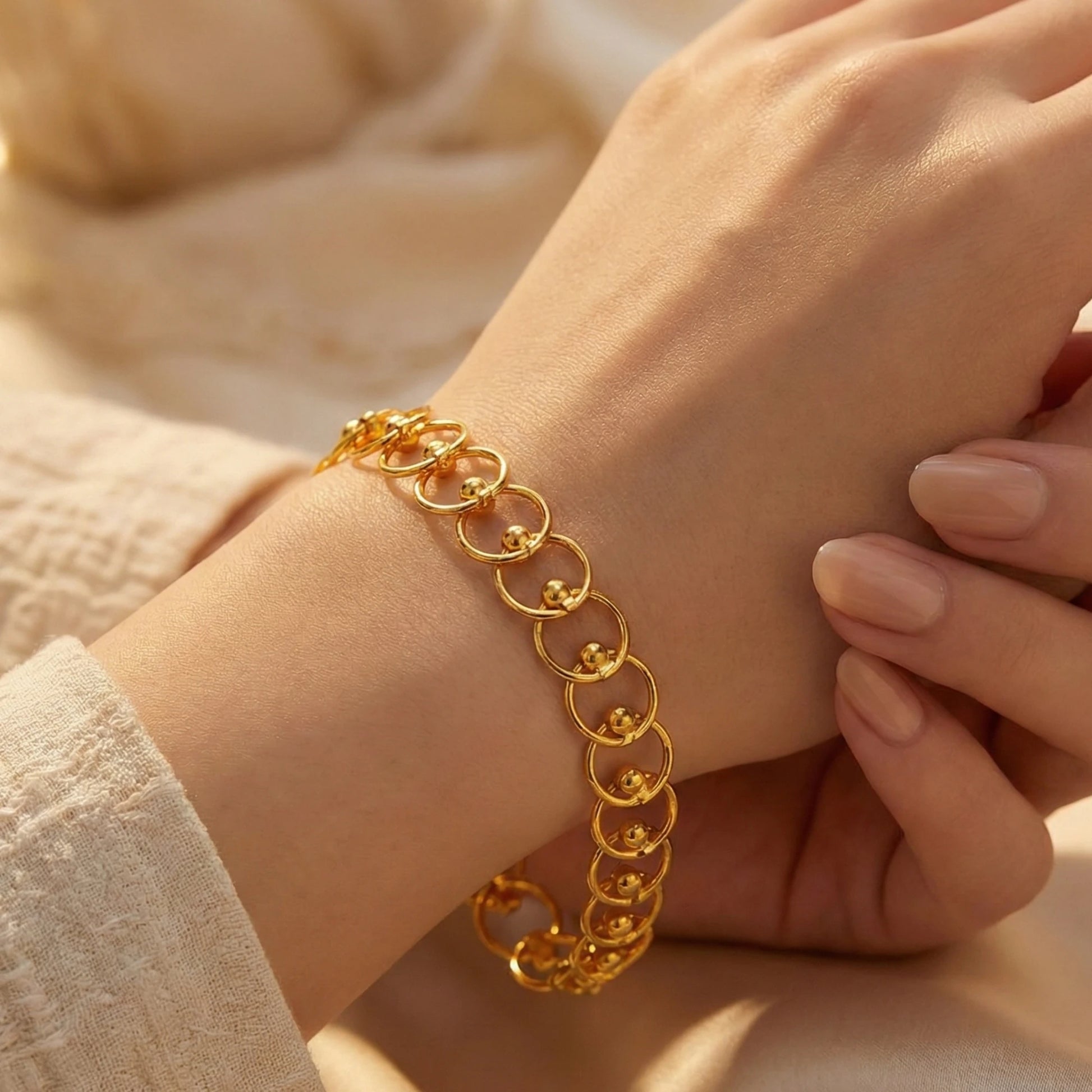 Gold plated chain bracelet on a wrist with a soft beige background
