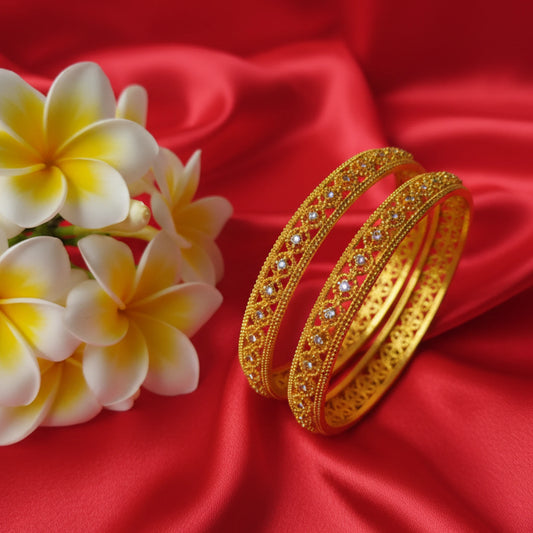 Gold plated bangles with open work filigree patterns and AD accents with white and yellow flowers on a red fabric background