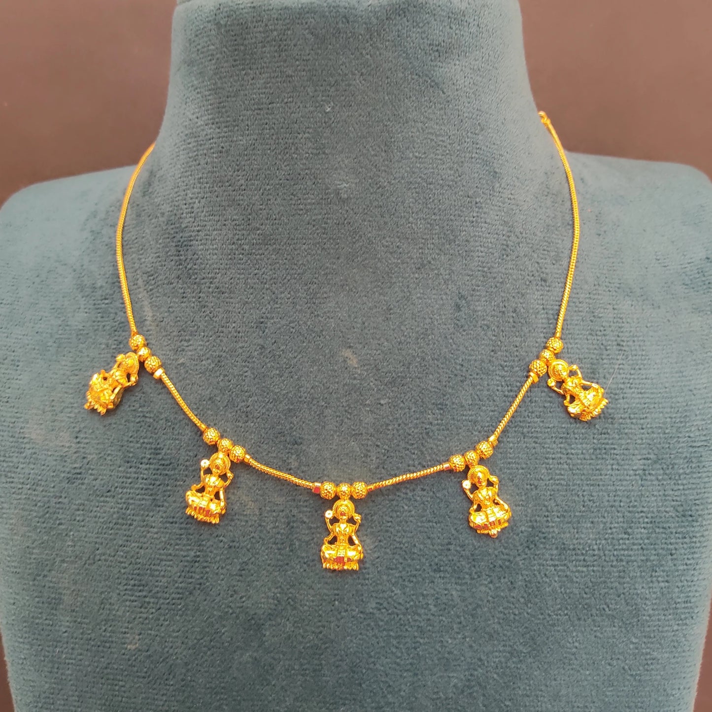 Gold plated necklace with hanging Lakshmi Pendant charms on a mannequin bust.