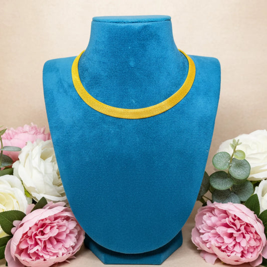 Blue velvet jewelry display with Kerala Kasavu Necklace surrounded by pink and white flowers on a beige background