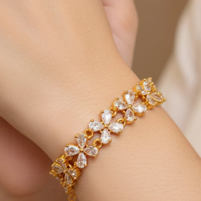 Gold plated bracelet with clear stones on a wrist against a neutral background