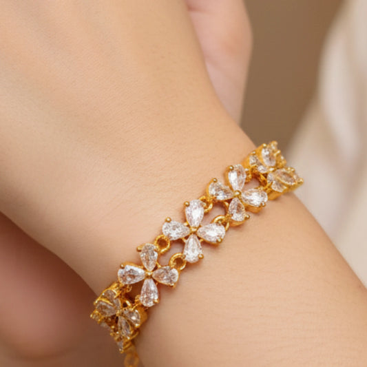 Gold plated bracelet with clear stones on a wrist against a neutral background