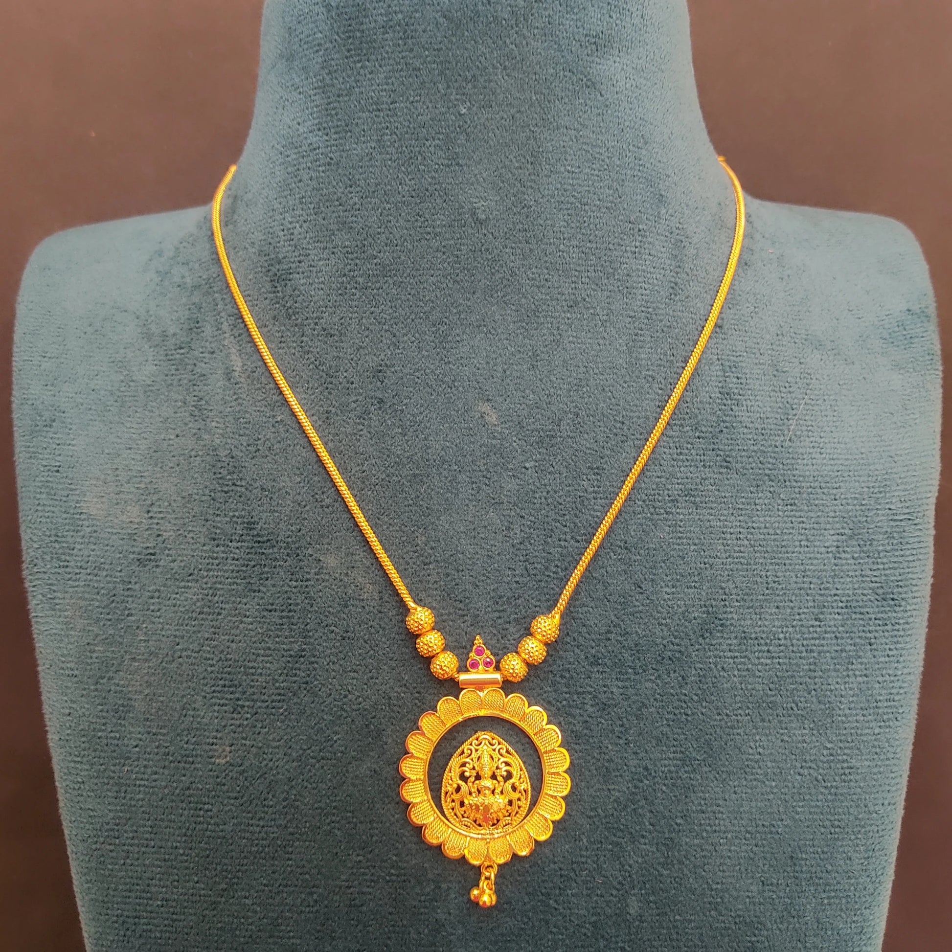 Gold plated necklace with a decorative pendant and a matte finish Lakshmi on the Lotus Pendant on a mannequin bust.