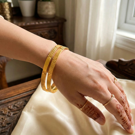 Hand wearing gold plated bangles with a blurred indoor background