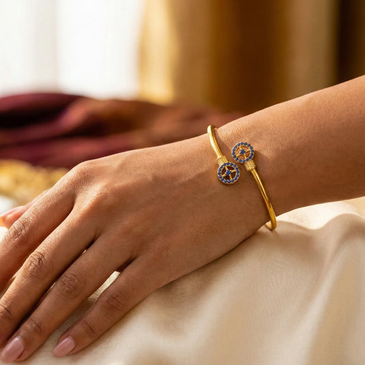 Gold plated bracelet with circular design on a person's wrist against a neutral background