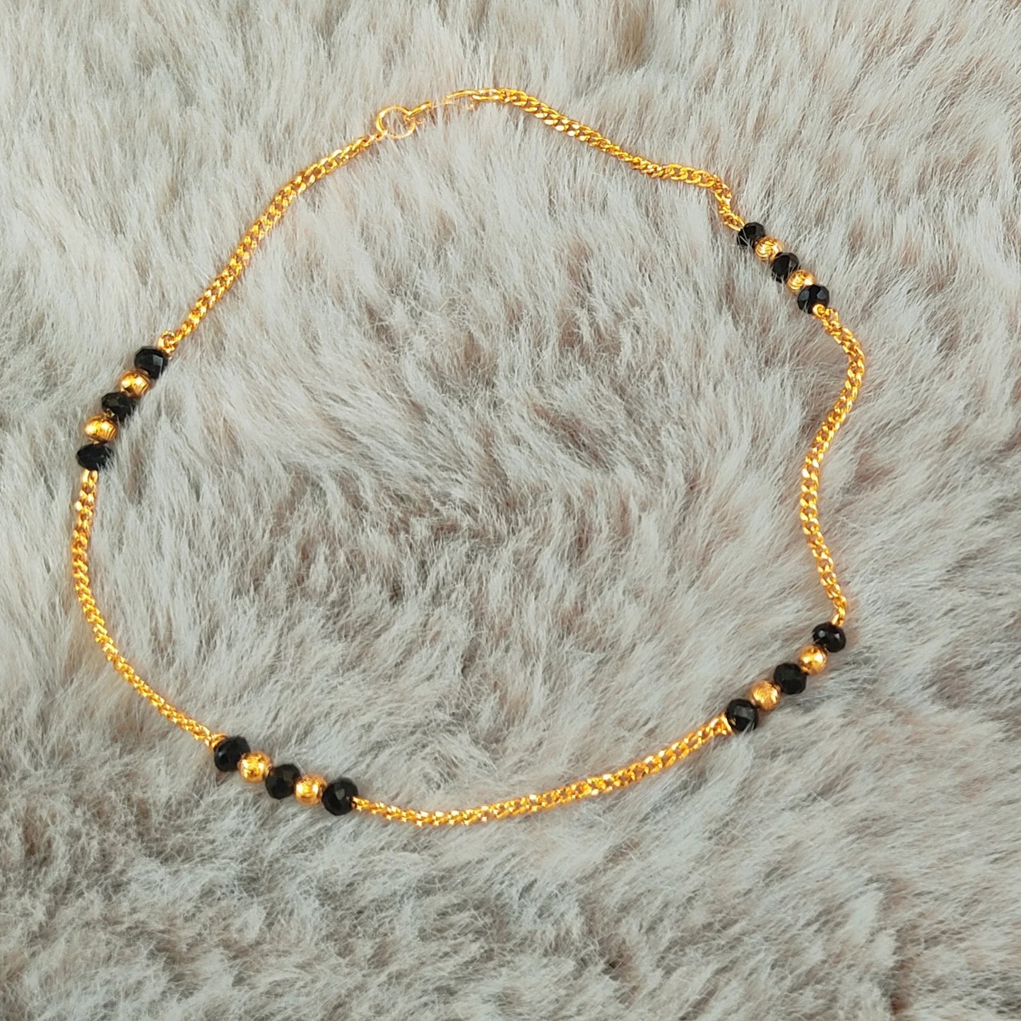 Gold plated Anklets with Nazariya black beads on a fur background