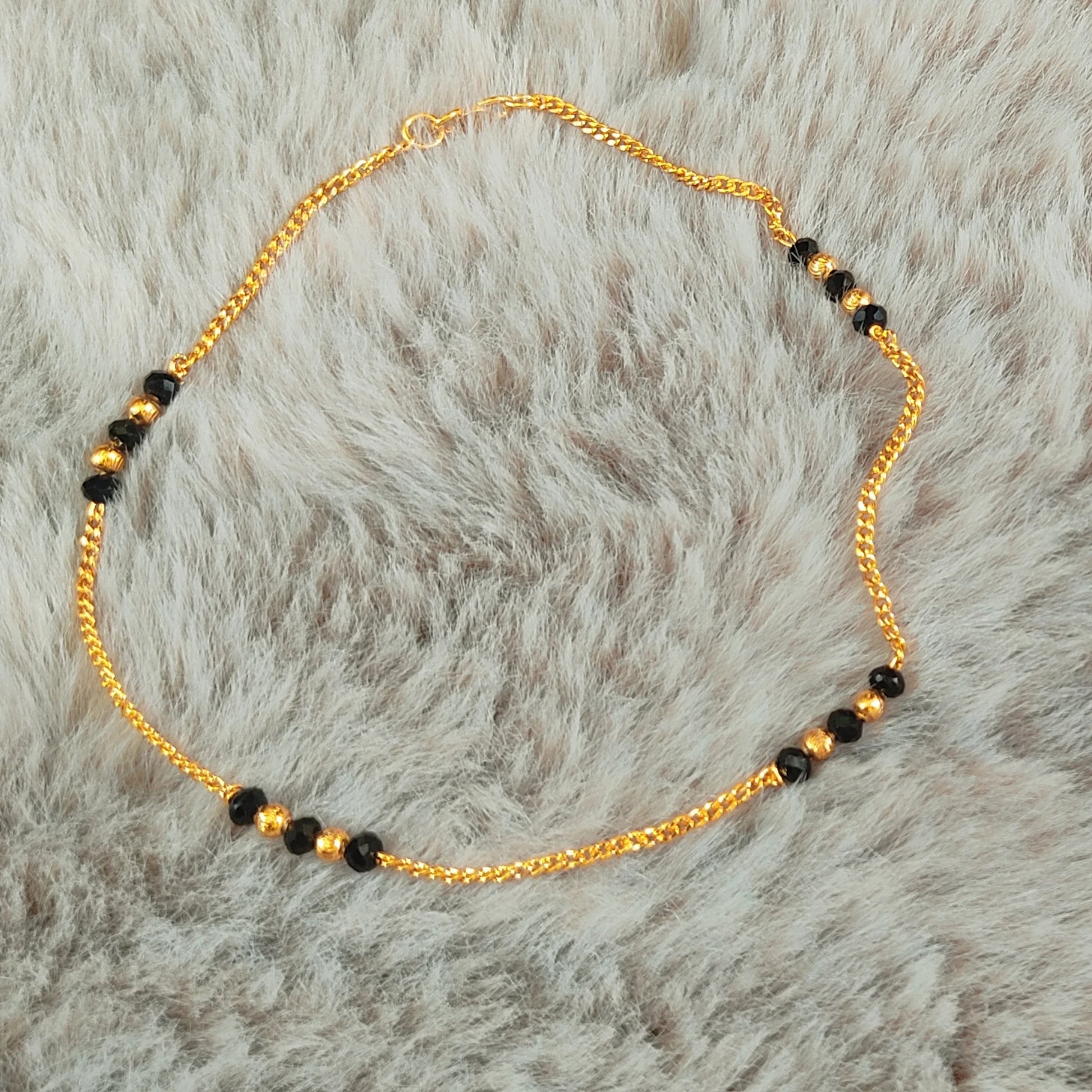 Gold plated Anklets with Nazariya black beads on a fur background
