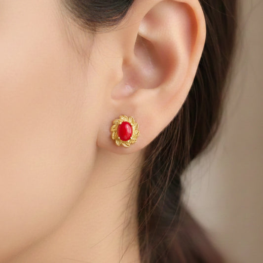 Gold plated earring with a red gemstone worn by a person