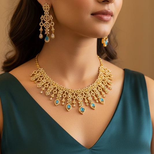 Woman wearing a gold-plated necklace with blue stones and matching earrings against a neutral background