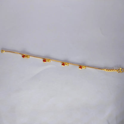 Gold plated bracelet with ruby red heart charms on a light gray background