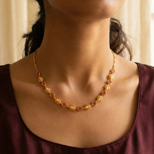 Gold plated necklace worn by a person with a neutral background