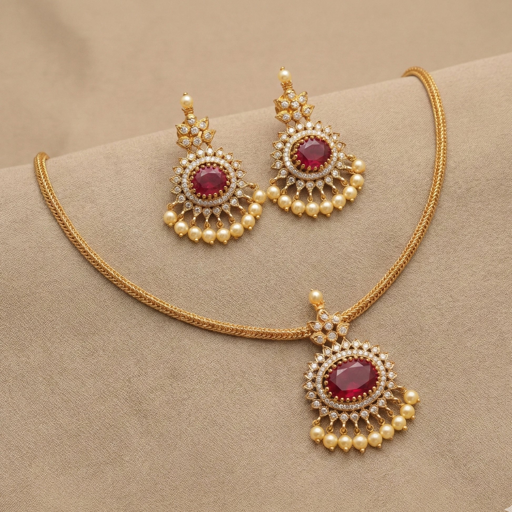 Gold toned necklace with red gemstones and pearl-like beads on a beige background