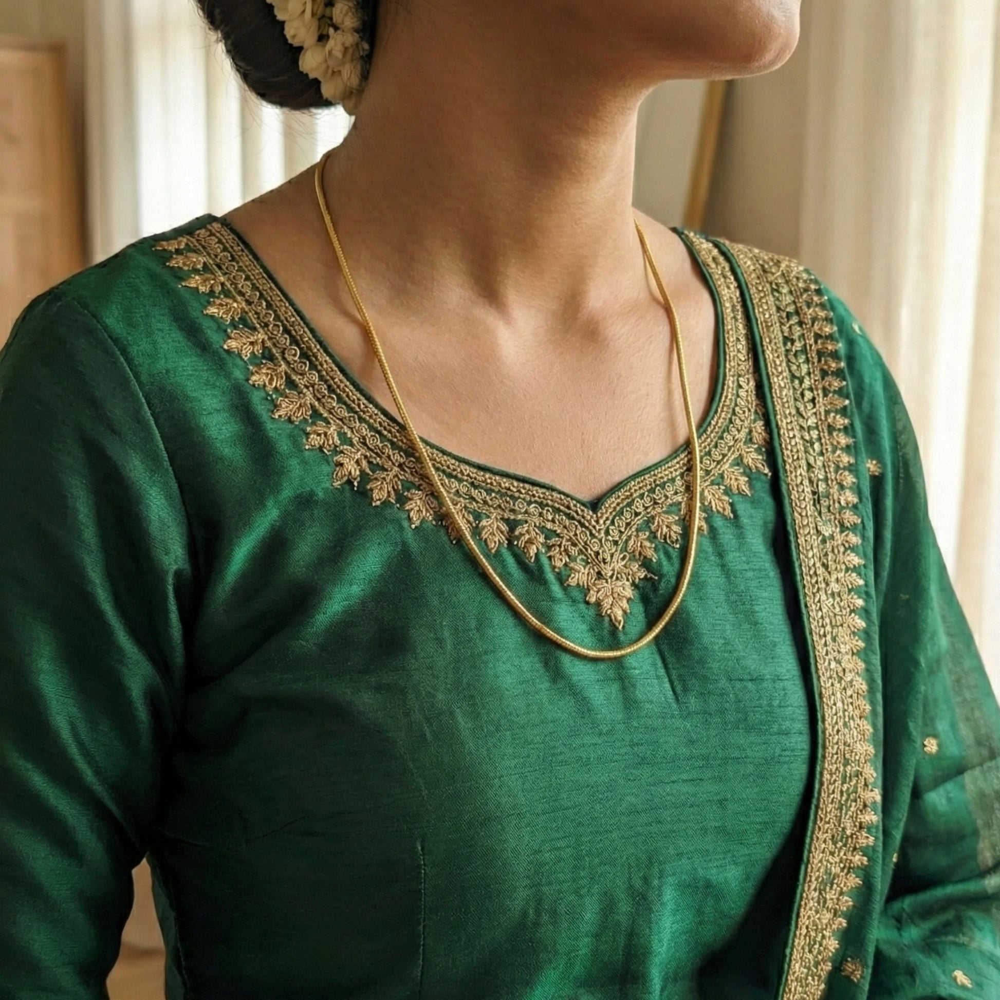 Gold Plated Neck chain in a Green traditional outfit with gold embroidery on a blurred background