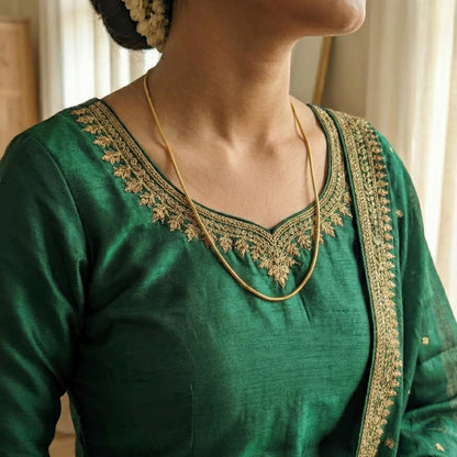 Gold Plated Neck chain in a Green traditional outfit with gold embroidery on a blurred background