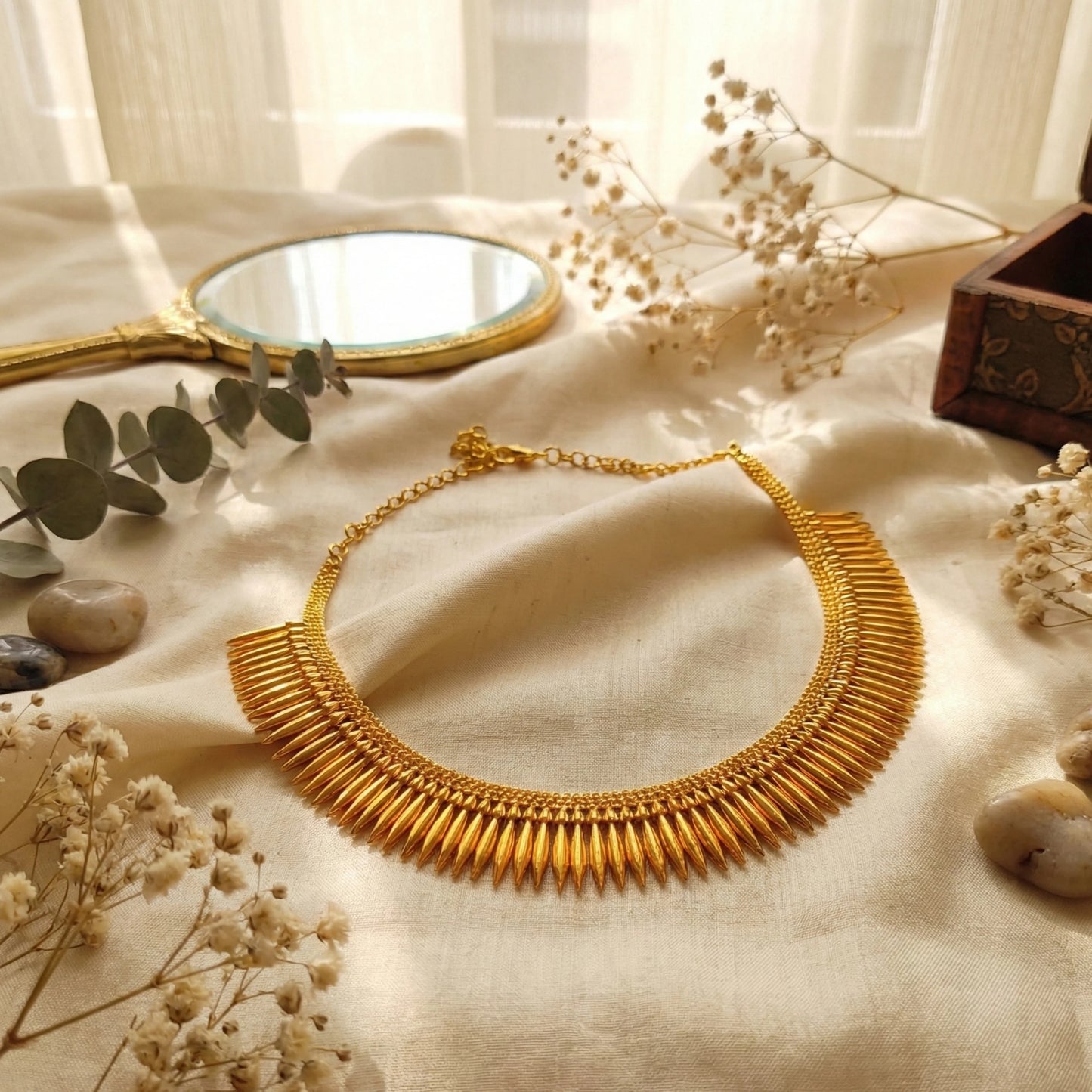 Gold plated necklace on a textured surface with decorative elements