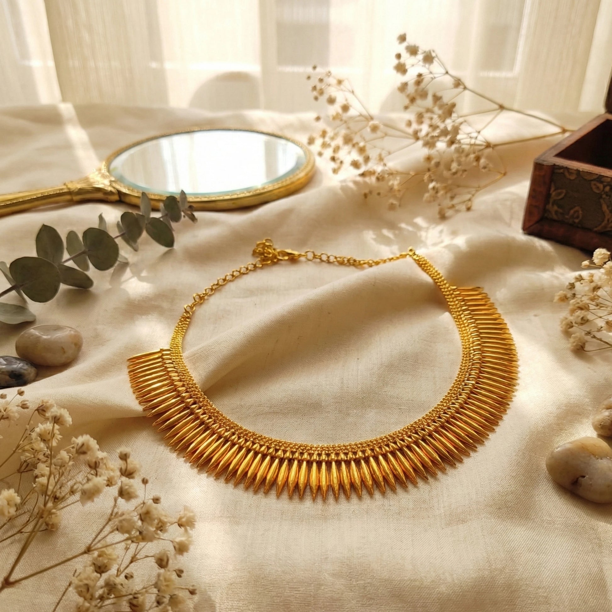 Gold plated necklace on a textured surface with decorative elements